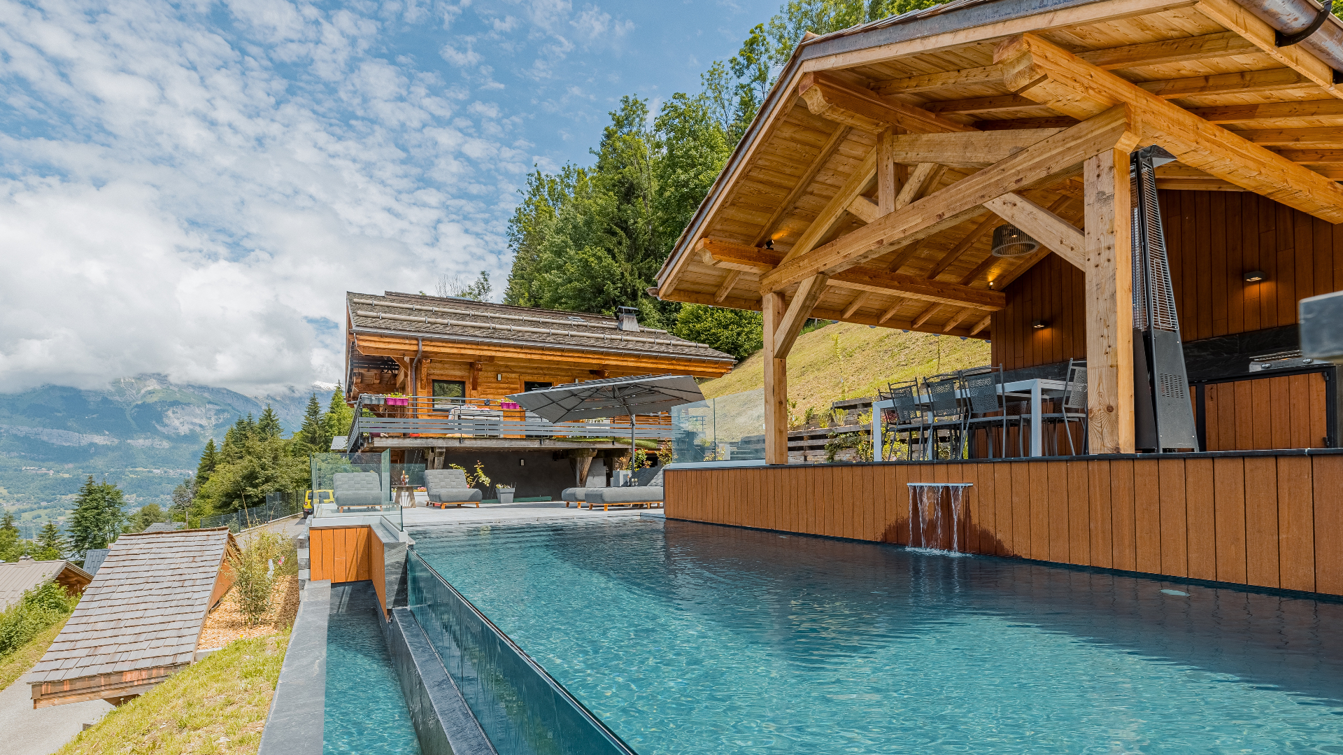 Piscine de chalet en montagne avec cascade et terrasse en bois