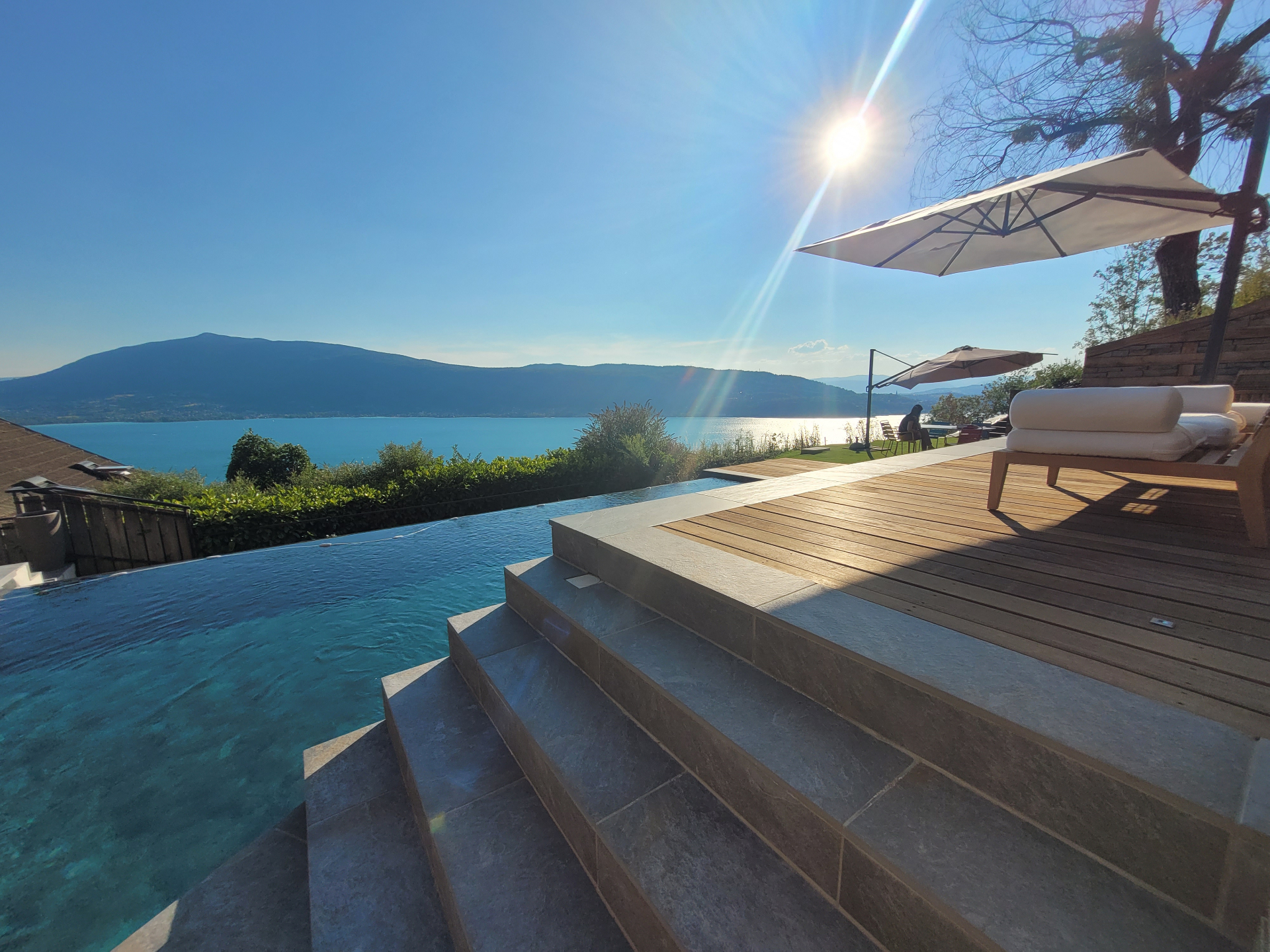 Piscine à débordement avec vue panoramique sur le lac d'Annecy au coucher de soleil